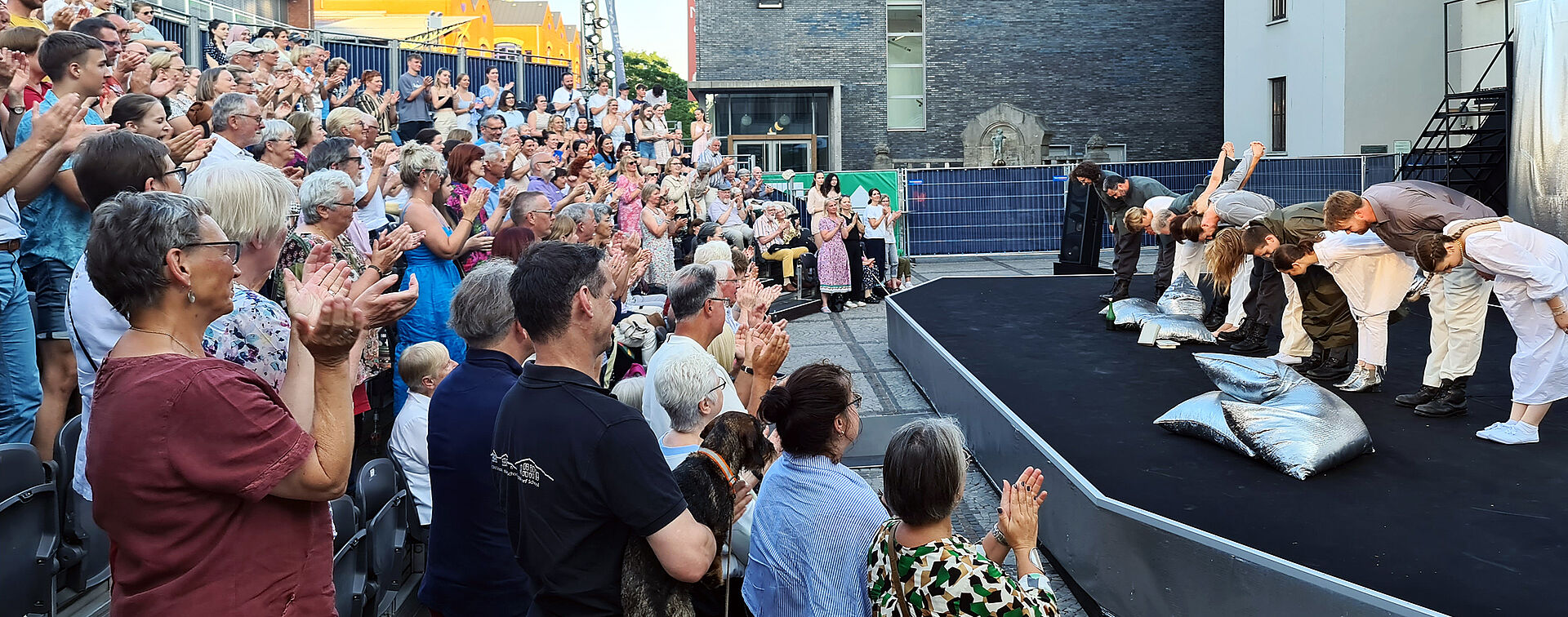 Sommerbühne 2023 (Foto: Lars Tietje) Applaudierendes Publikum vor dem sich verbeugenden Ensemble von "Cyrano de Bergerac" auf der Sommerbühne vor dem Stadttheater Bremerhaven.